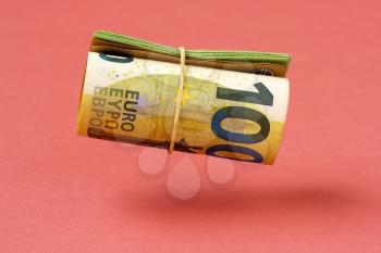 Roll of euro currency floating over pink background