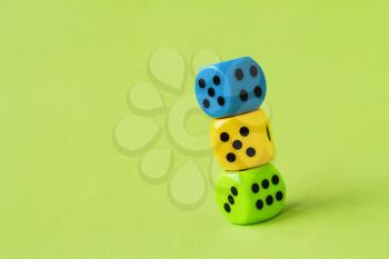 Stack of colorful dice on green background. Copy space.