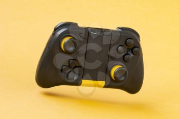Video game controller falling on the yellow background