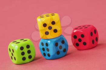 Four colorful dice on pink background. Close-up view.
