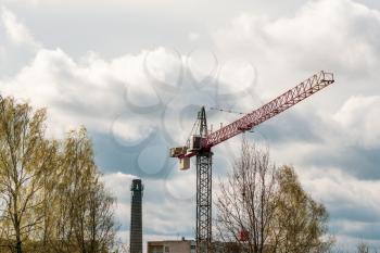 Construction site with a tower crane with a spring trees in a foreground