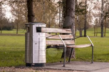 Wooden bench and metal trash can in the city park. Modern urban style of public place.