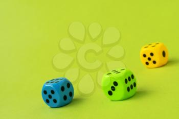 Three colored dice on green background. Copy space.