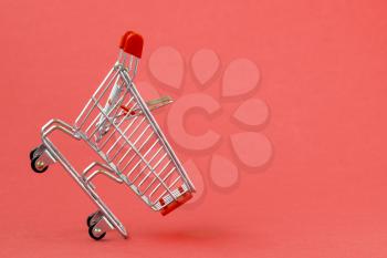 Empty shopping cart on a red background. Grocery hand cart.