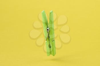 Green wooden clothes peg over yellow background