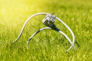 Grey electric cable on a green grass. Eco, bio, energy saving concep.