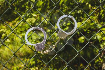 Handcuffs hanging on the metal fence with nature background