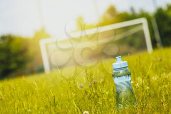 Sport bottle of fresh water on football field grass
