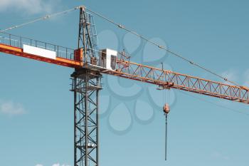 Tower crane with a boom and a crane operator's cab over a sky background