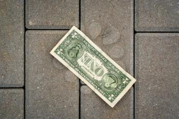 One dollar banknote lying on the ground. Lost money.