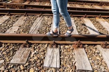 Woman walking on the train tracks with summer sandals. Travel concept.