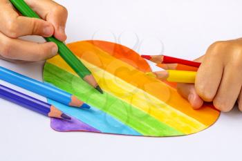 A child coloring multicolored heart, the concept of lgbt friendly