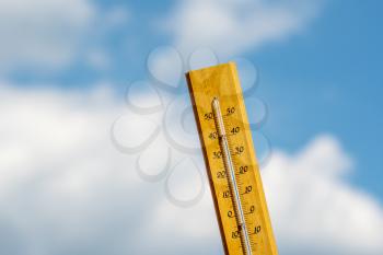 Thermometer on a hot summer day. Mercury thermometer marking 37 degrees Celsius in a sunny day. Summer heat shown on mercury thermometer against the blue sky. 
