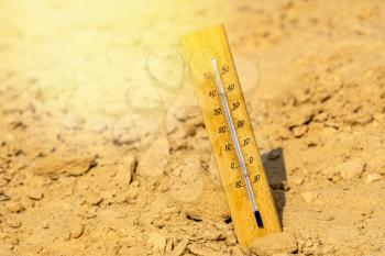 Thermometer shows very hot summer temperature in dry desert sand dunes. Climate change/global warming/desert concept.