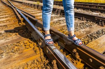 Woman walking on the railroad with summer sandals. Travel concept.