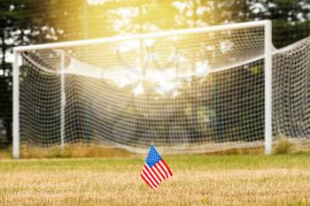 USA flag on a soccer field with empty gates on background. National United States of America flag waving outdoor
