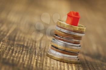 Small red house standing on stacks of coins.Close-up view. Property investment and house mortgage financial concept