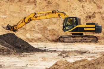 Excavator during earthmoving at open pit. Construction machinery and earth-moving heavy equipment for excavation, loading.