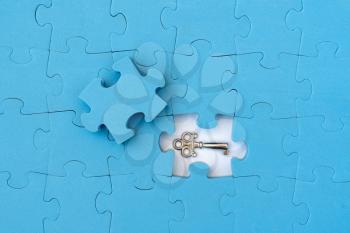 Find key of of solution. Blue jigsaw puzzle with small key.