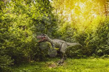 Statue of realistic dinosaur in a forest with sunlight