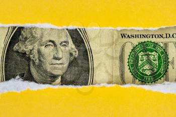 US currency macro peeking through torn yellow paper