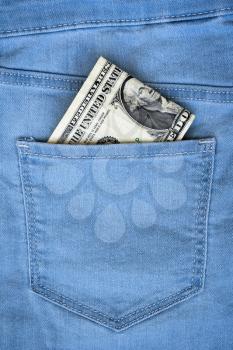 One dollar note in the back pocket of blue jeans. Dollar bill in jeans pocket close-up.