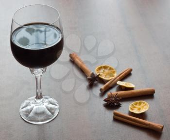 Red wine glass on table with cinnamon and lemon
