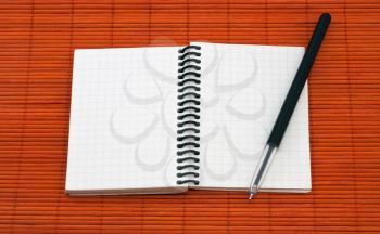 Open notebook with pen on red wooden background
