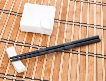 Chopsticks and bowl on brown bamboo background