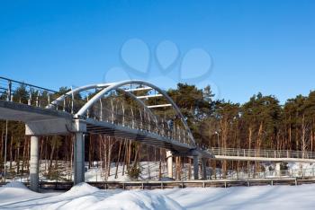 Walking bridge in winter forest over the highway