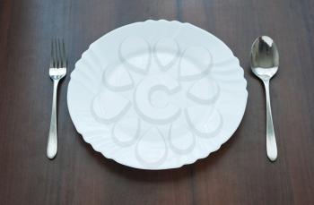 Plate with fork and spoon on wooden table