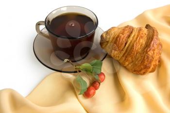 Brown glass cup with tea, croissant and wild apples on the beige light fabric isolated on a white background