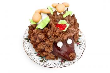 Cake in the form of a hedgehog, adorned with green leaves with cream, mushrooms from the biscuit and meringue, berries, jelly on a plate isolated on a white background