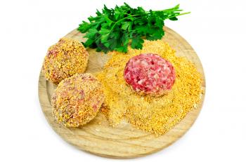 Three homemade meatballs, bread crumbs, a bunch of green parsley on a circular wooden board isolated on white background