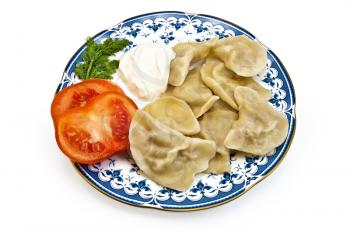 Dumplings, two slices of tomato, a sprig of dill and sour cream on the porcelain plate isolated on white background