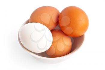 One white and three brown eggs in a bowl is isolated on a white background