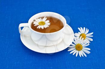 Herbal tea in a white cup of chamomile on blue napkin