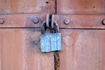 The old steel door closed on the hanging metal lock