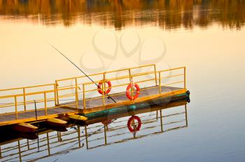 Pierce with yellow railings and wooden flooring on the water, spinning, two red lifebuoys at dawn