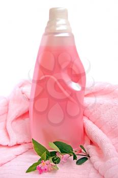 A bottle of conditioner pink twig with pink flowers and green leaves, pink towel on a white background