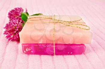 Two homemade pink soap, tied with hemp rope, two flowers pink clover on the terry towel