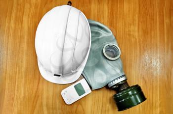 The white helmet, gas mask and a dosimeter on the background of a wooden tabletop