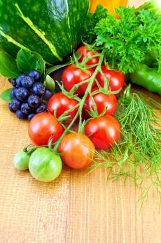 Sprig of small red tomatoes, pumpkin, fennel, parsley, green pepper, brush chokeberry, yellow sweet pepper, cucumber on a wooden board
