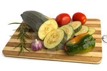Cut zucchini, red tomatoes, sweet peppers, garlic and tarragon sprig of green on a wooden board isolated on white background