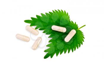 Two green nettle leaf, five beige capsules isolated on white background