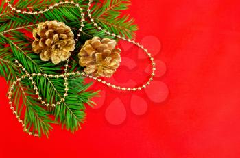 The fir branches, two golden cones, golden ornaments against red silk