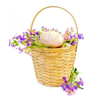 Chicken eggs in a wicker basket with pink and purple flowers isolated on white background