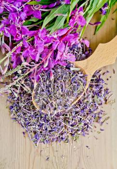 Fireweed flowers fresh and dry in a wooden spoon on a background of wooden boards