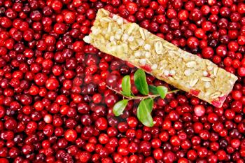 Muesli bar, twig with leaves and berries lingonberry background of lingonberry