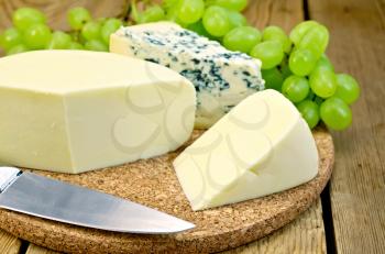 Blue cheese, suluguni, grapes, knife on background wooden board